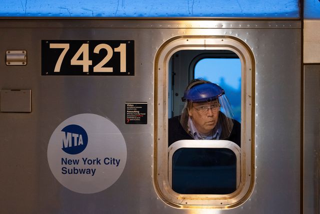 Subway conductor wears a plastic shield over his face